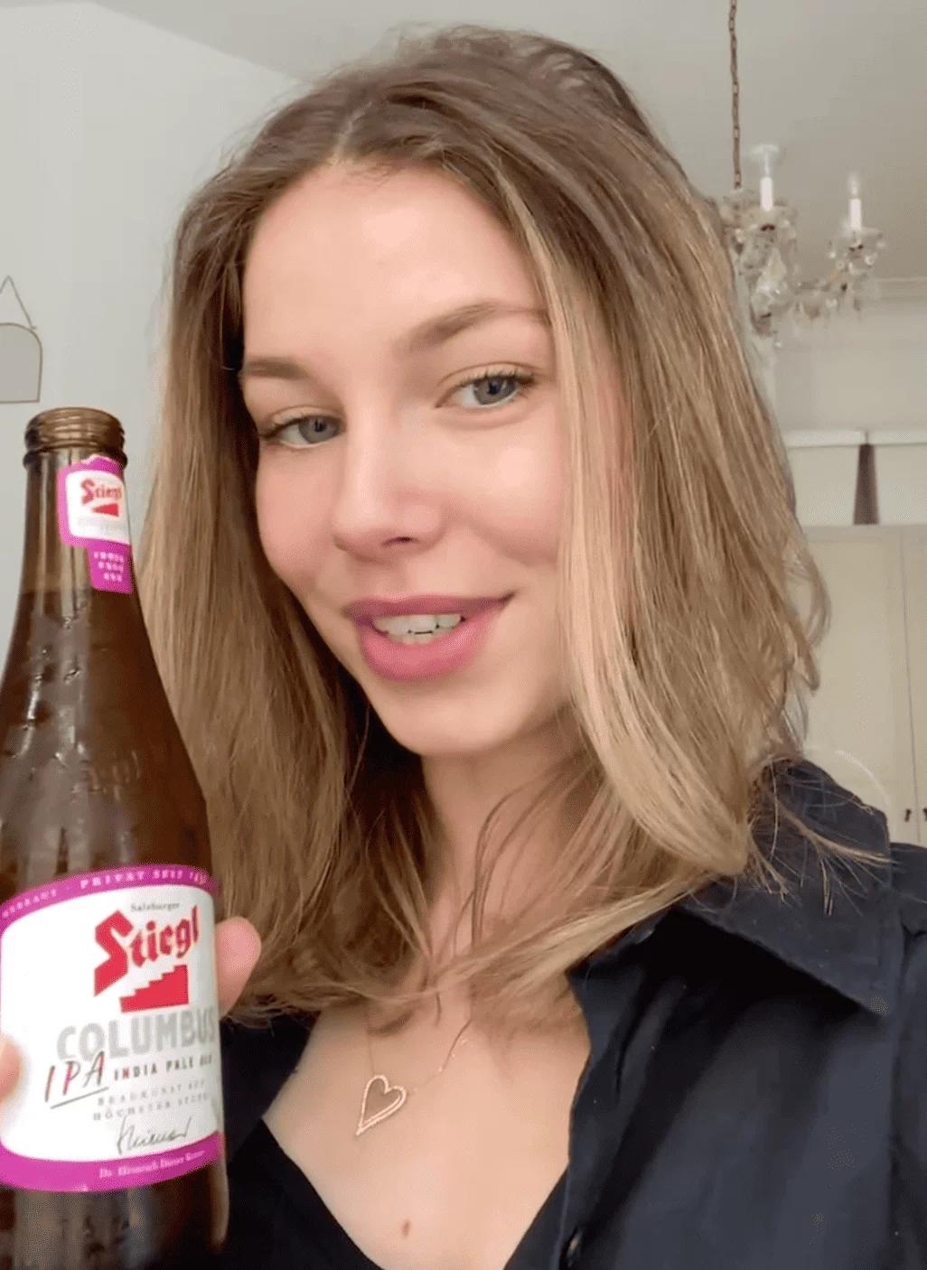 Screenshot aus einem UGC-Werbevideo: Eine junge Frau hält lächelnd eine Flasche Stiegl Bier in der Hand. Natürliche Umgebung, authentische Stimmung. Die grüne Flasche mit dem charakteristischen Stiegl-Logo ist deutlich erkennbar.